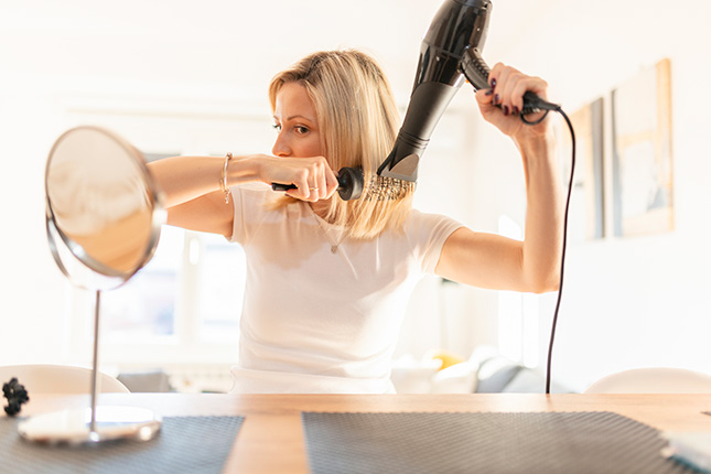 Je haar brushen met een borstel en een haardroger met concentrator